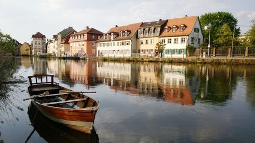 Boats moored in lake by houses against buildings