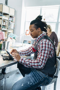 Side view of man using laptop at home