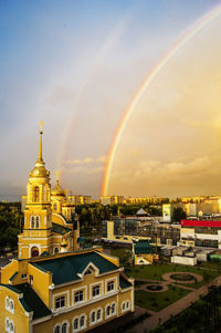 Rainbow over city against sky