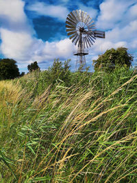 Low angle view of windmill on field against sky