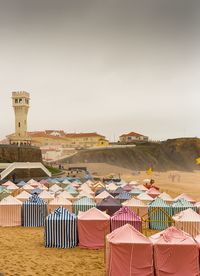 Hooded beach chairs on sand against clear sky