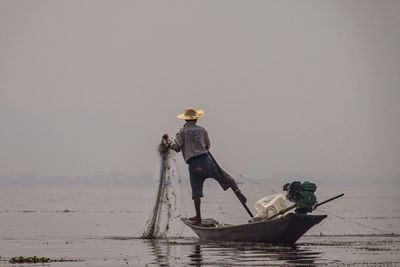 Man in boat on sea against sky