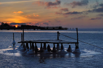 Pier over sea against sky during sunset