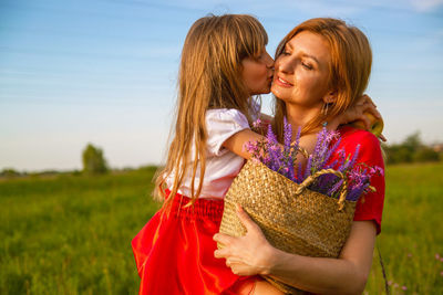 Portrait of smiling young mother with daughter on field