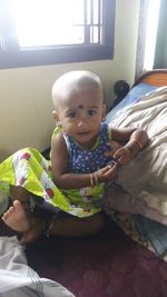 Portrait of cute baby girl on bed at home