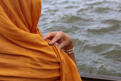 Cropped image of woman with headscarf by railing at liberty island against hudson river