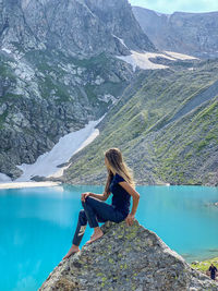 Woman sitting on rock looking at lake