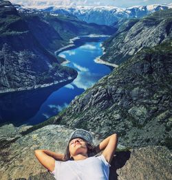 Woman relaxing with river and mountains in background