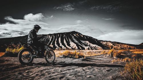 Man riding bicycle on mountain against sky