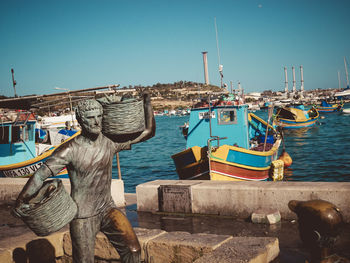 Fishing boats moored at harbor against clear sky