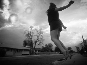 Silhouette of woman jumping against sky