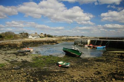 Boats moored at harbor against sky