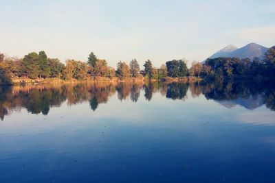 Reflection of trees in calm lake against sky