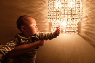Close-up of cute boy touching chandelier