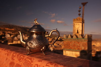 Metallic teapot on table against town