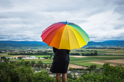 Rear view of man standing on landscape against cloudy sky