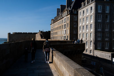 People walking on staircase amidst buildings in city