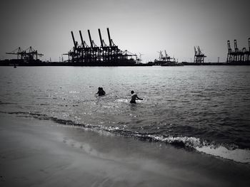 Silhouette people on beach against clear sky