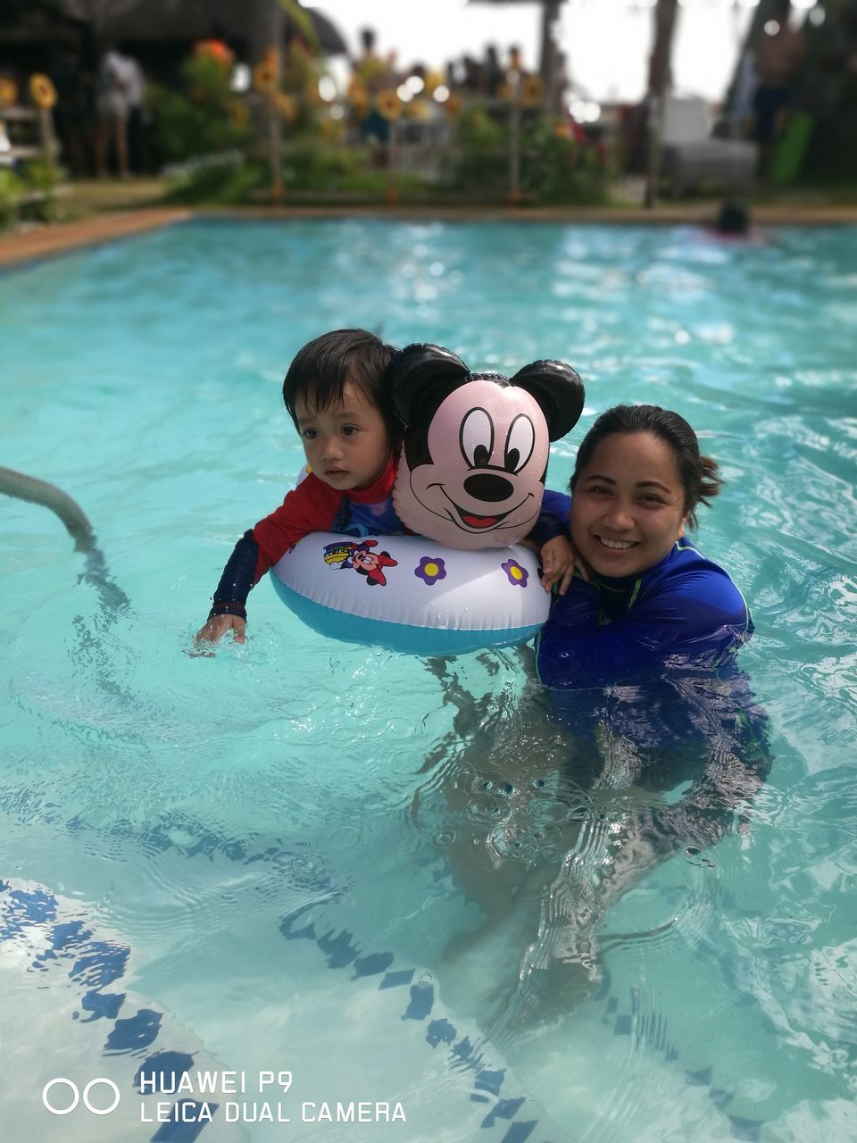 PORTRAIT OF HAPPY MOTHER AND DAUGHTER AT SWIMMING POOL