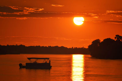 Silhouette boat in sea against sky during sunset on zambezi river in zambia