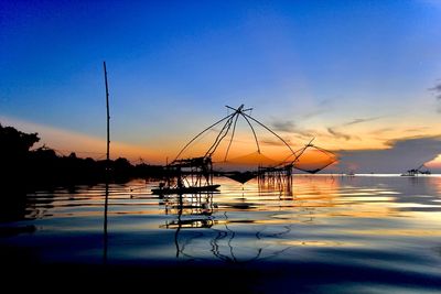 Silhouette sailboats in sea against sky during sunset