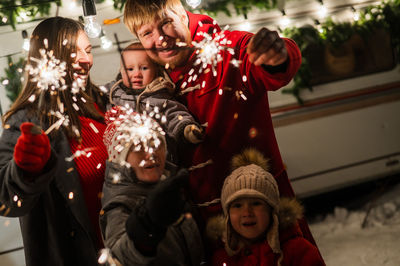 Cheerful family holding sparklers at night