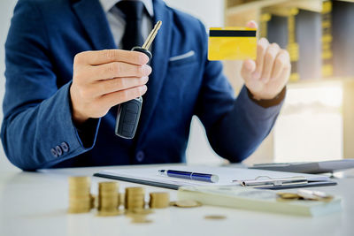 Midsection of insurance agent holding keys over table