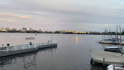 Sailboats moored in harbor against sky in city