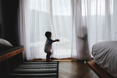 Rear view of woman sitting on bed at home