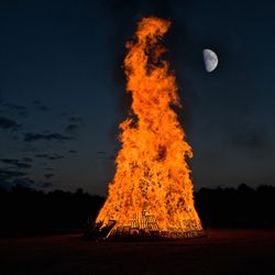 Bonfire on field against sky at night