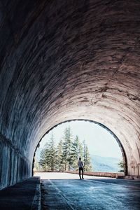 Rear view of man walking under bridge