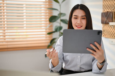 Portrait of young woman using laptop at home