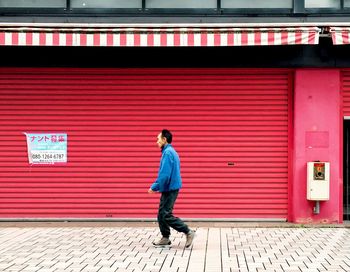 Full length side view of a man walking on footpath