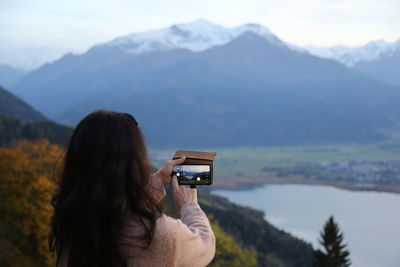 Side view of woman photographing against mountain