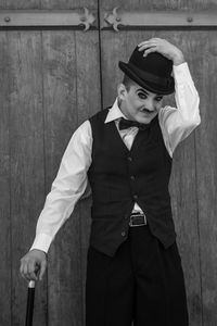 Portrait of young man in costume standing against door