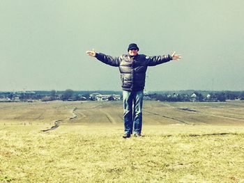 Full length of a man with arms outstretched against sky