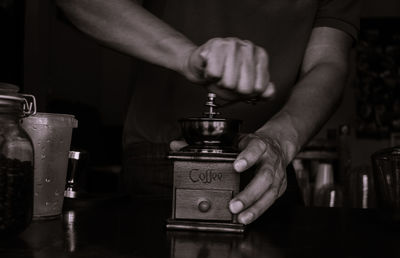 Midsection of man holding wine glass on table