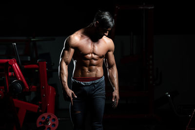 Rear view of shirtless man exercising in gym