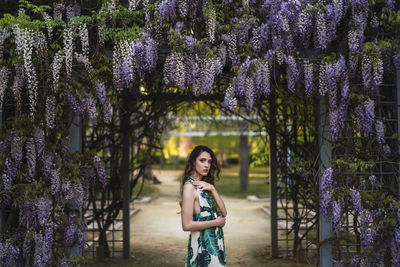 Portrait of woman standing by purple flowering plants