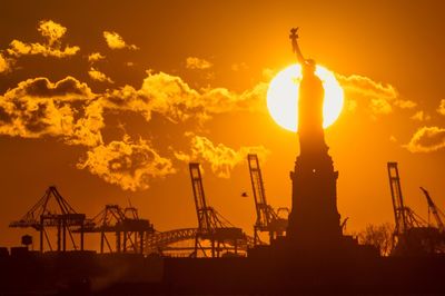 Silhouette statue against factory during sunset