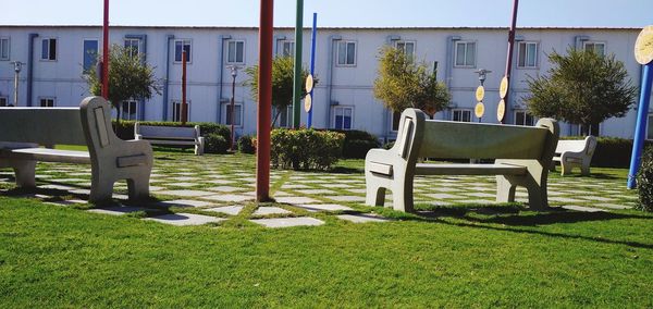 Empty chairs and table in lawn by building