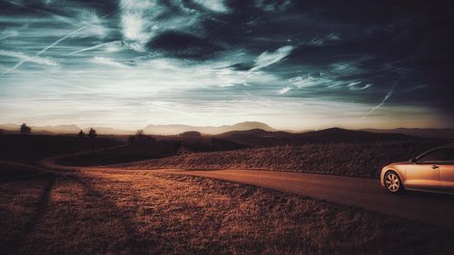 Car on sand against sky during sunset