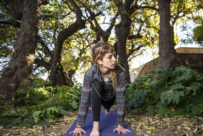 Thoughtful woman practicing yoga in forest