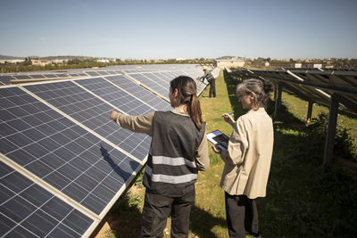 Female engineer showing solar panels to senior entrepreneur during visit at power station