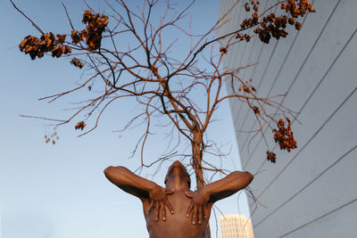 Low angle view of person by plants against sky