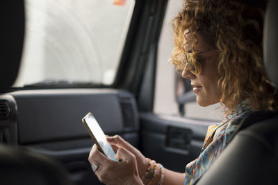 Side view of woman using smart phone in car
