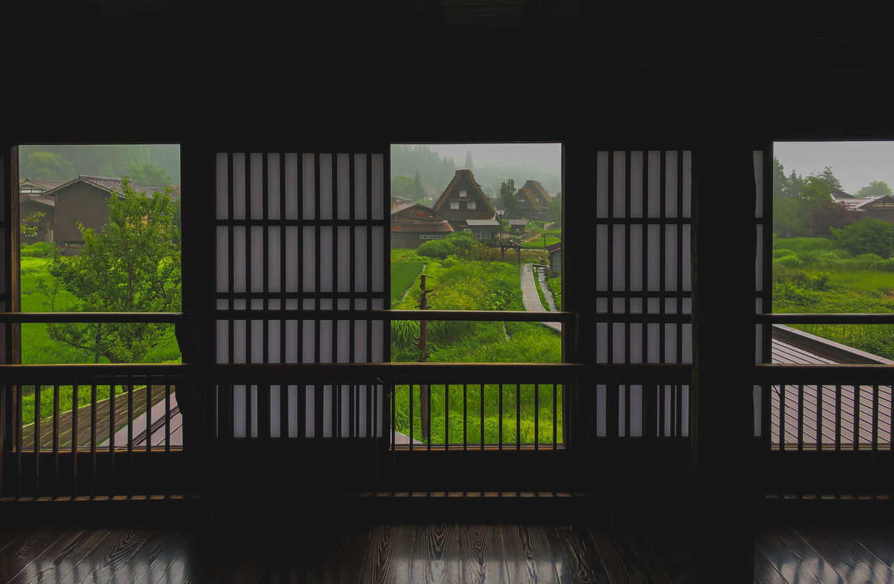 TREES AND BUILDINGS SEEN THROUGH WINDOW