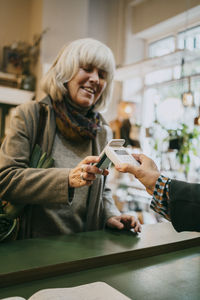 Senior woman paying via tap to pay method while doing shopping at store