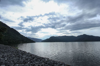 Scenic view of lake and mountains against cloudy sky