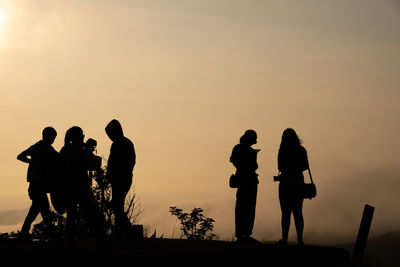 Silhouette people standing against sky during sunset